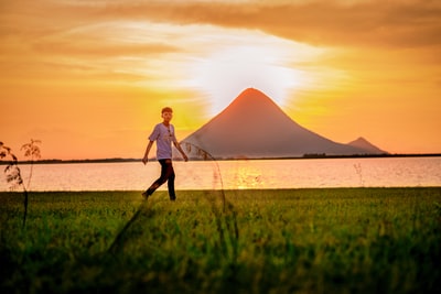 At sunset, dressed in a pink jacket woman standing on the green grass
